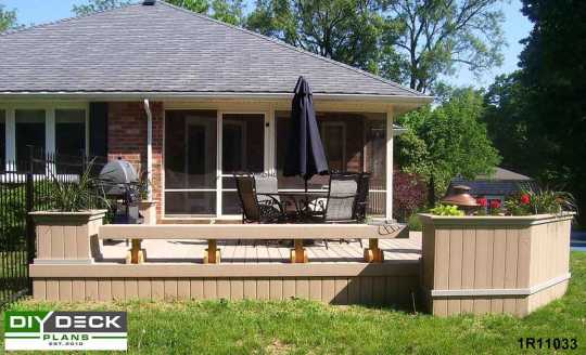 Front view of a single level composite deck with a bench and flower boxes.