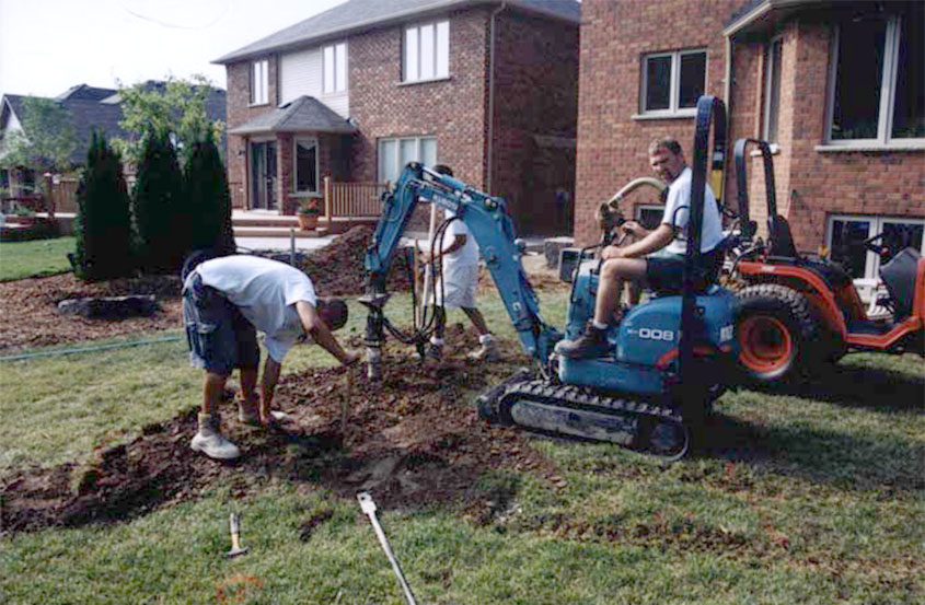 A crew digging post holes for a deck.